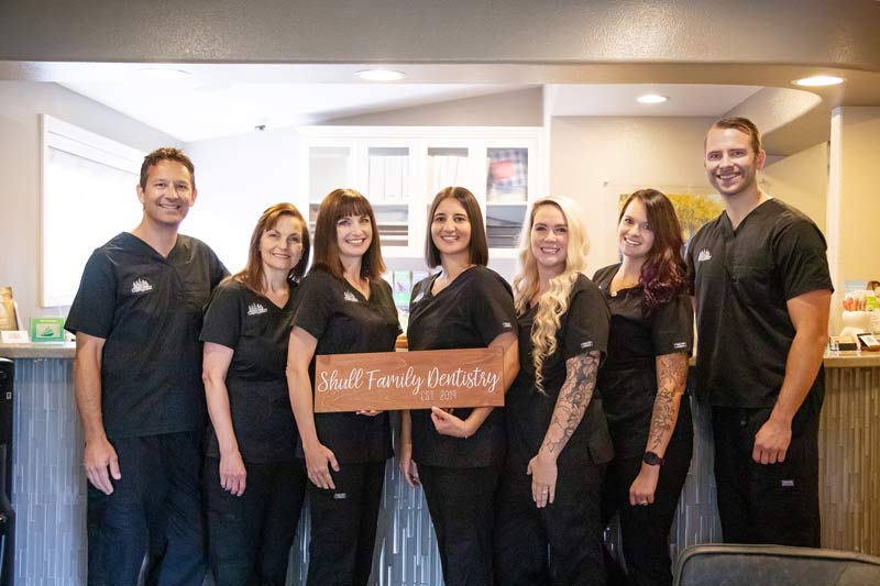 Doctors and team at Shull Family Dentistry holding practice sign in Salem, Or